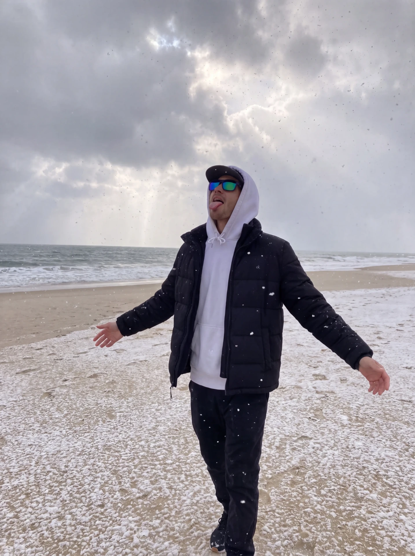Snow falling on a Hamptons ocean beach in winter, hoodie and puffer weather