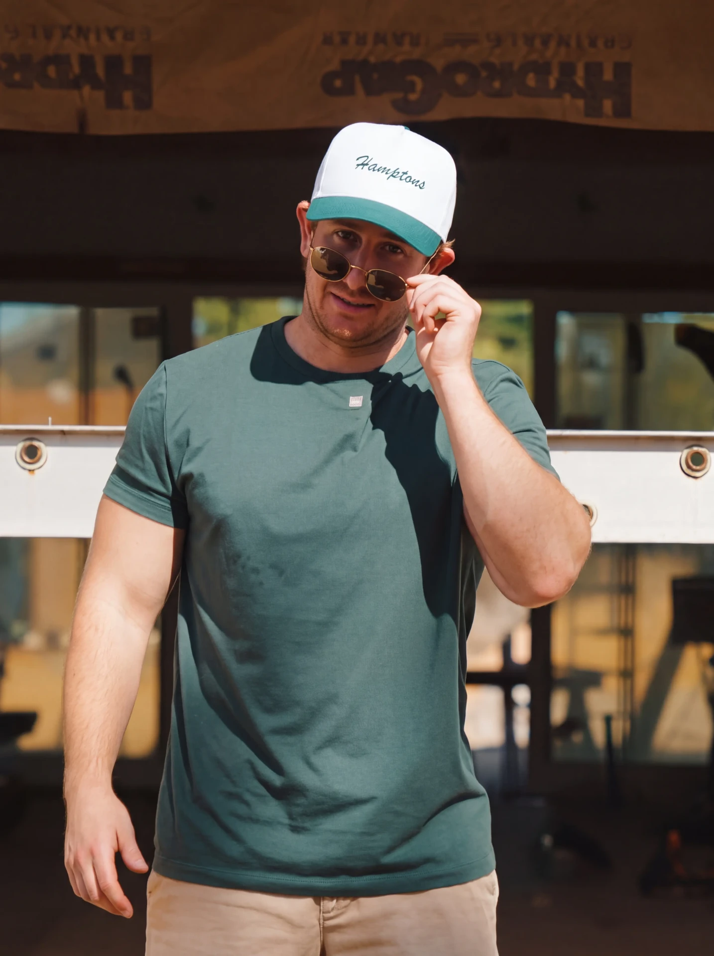 Hamptons script trucker hat in white and green with a green tee